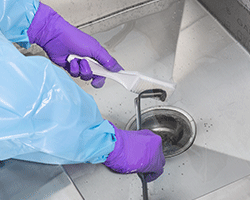 Manual cleaning surgical instruments at a sink.