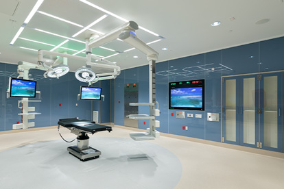 Operating room with surgical table, overhead lights, monitors, and storage cabinets