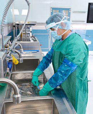 SPD Technician at Sink with Instruments