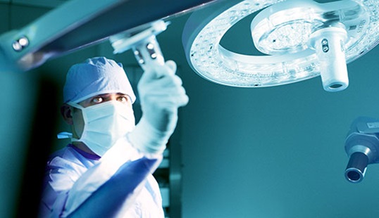 Surgeon working in the operating theatre with STERIS surgical lighting.
