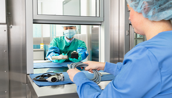 Sterile processing technician sending equipment through the pass-through window